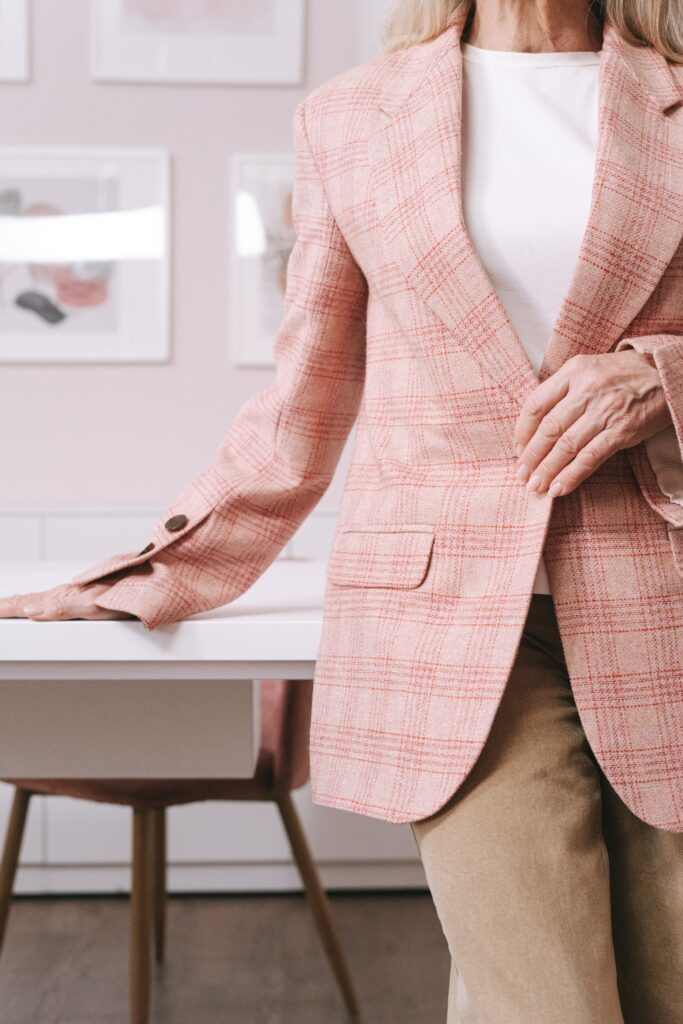 woman in pink checkered blazer leaning on table 