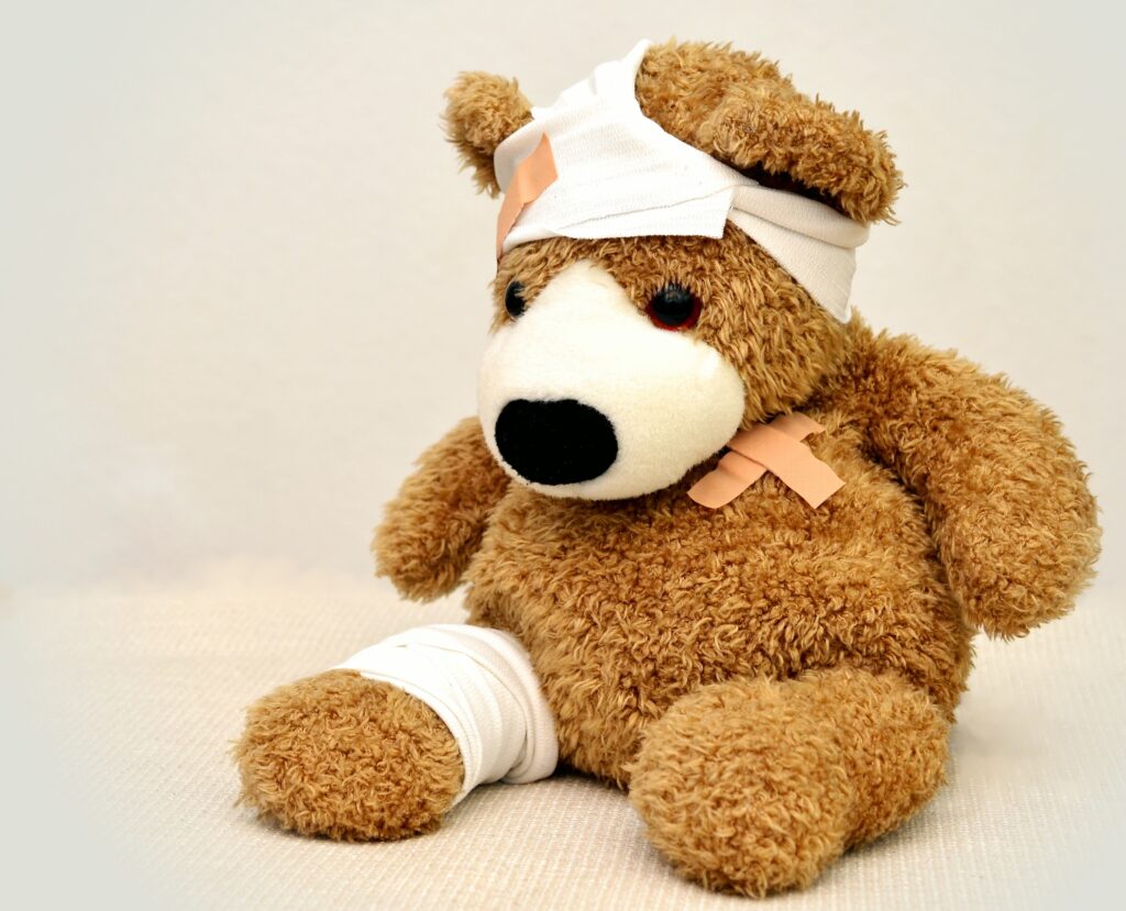 brown teddy bear sitting upright with multiple bandages highlights the need to learn first aid in self-sufficient living
