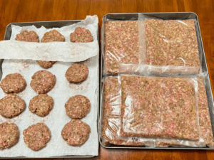 batch prepped ground meat & seasonings formed into homemade burger patties & vacuum sealed flat packs ready for the freezer