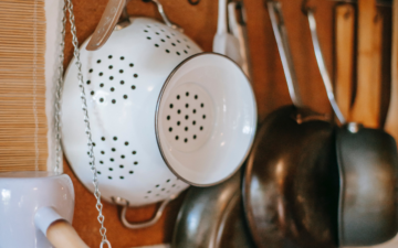Hooks installed underneath a range with collander and several pots hanging on them is the perfect space saving solution for kitchen organization in small spaces