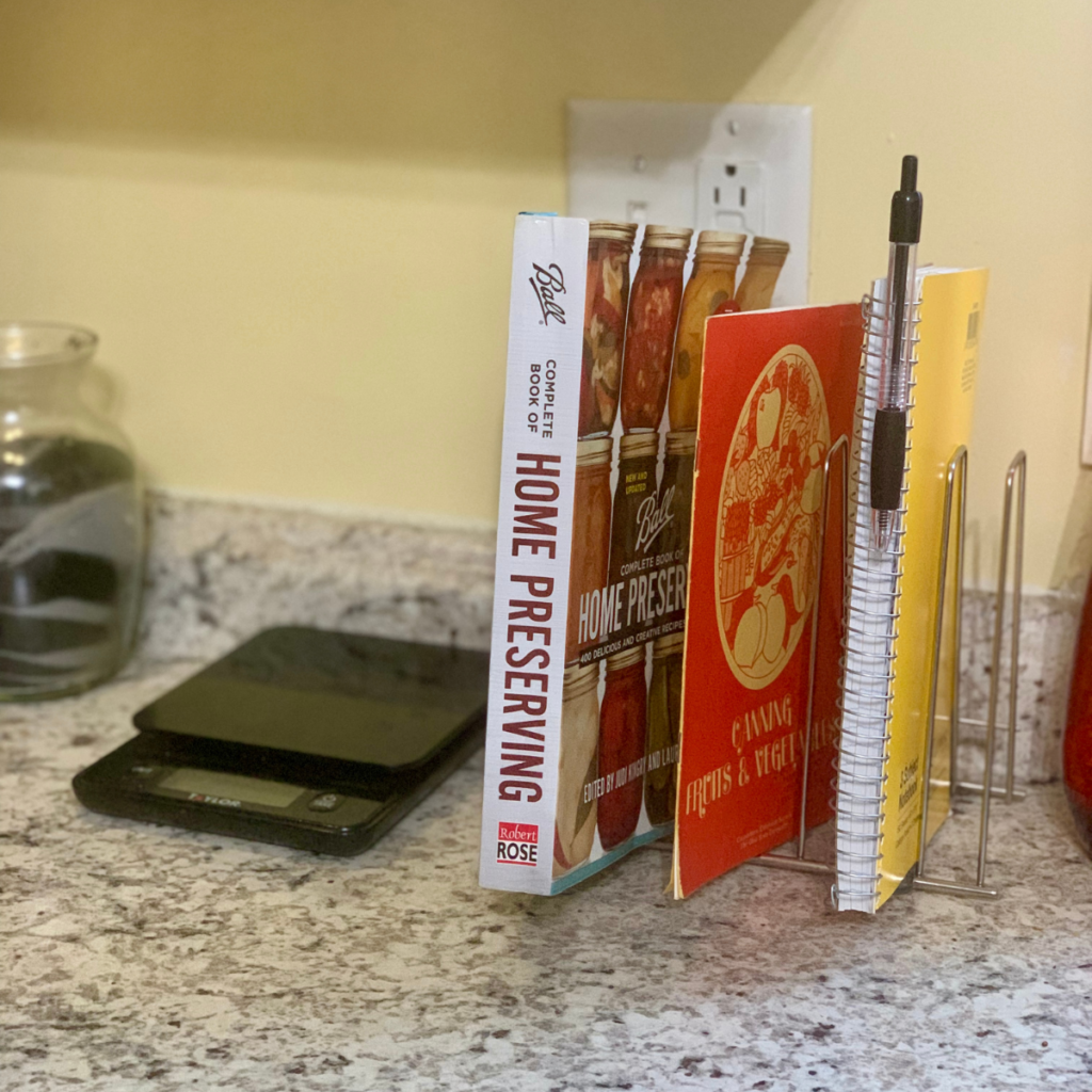 a dish drying rack holding small books and a kitchen logbook is an example of using multi-functional tools to maximize kitchen organization in small spaces