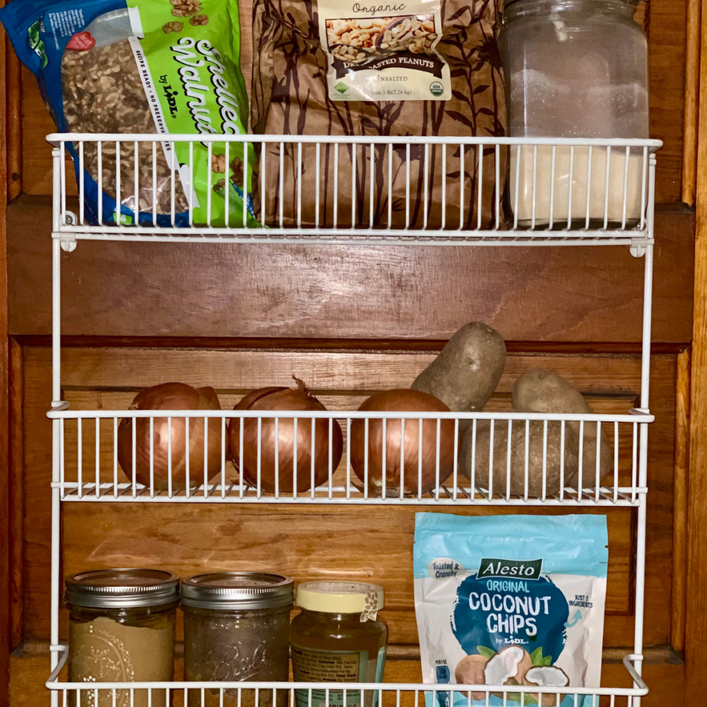 shelving houses long-term pantry storage foods that need airflow and no moisture like potatoes and onions shown here. Also shown is bulk items like dried nuts and flours in see-through container.