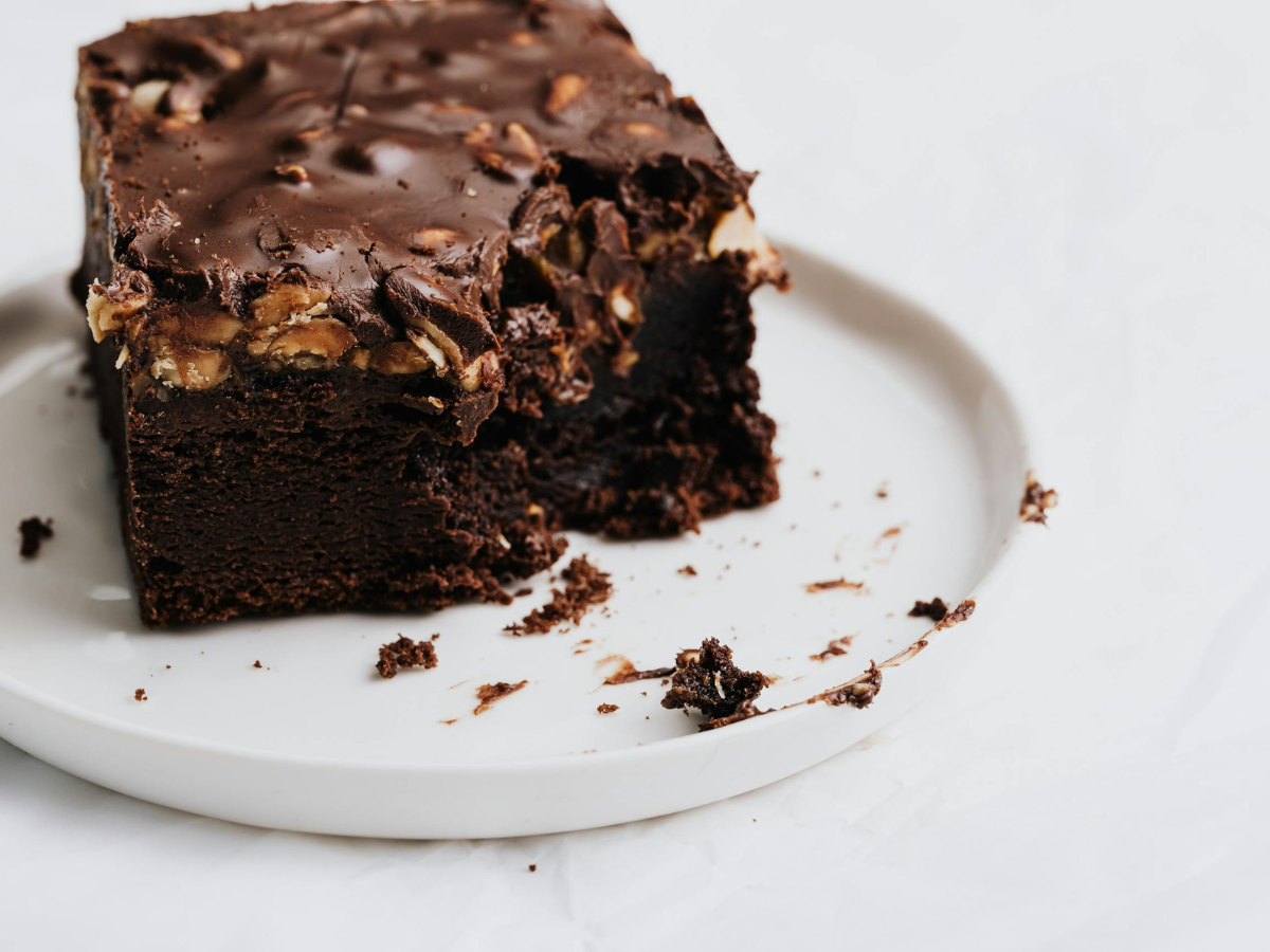 Decadent chocolate brownie with nuts on a white plate, perfect for dessert lovers.